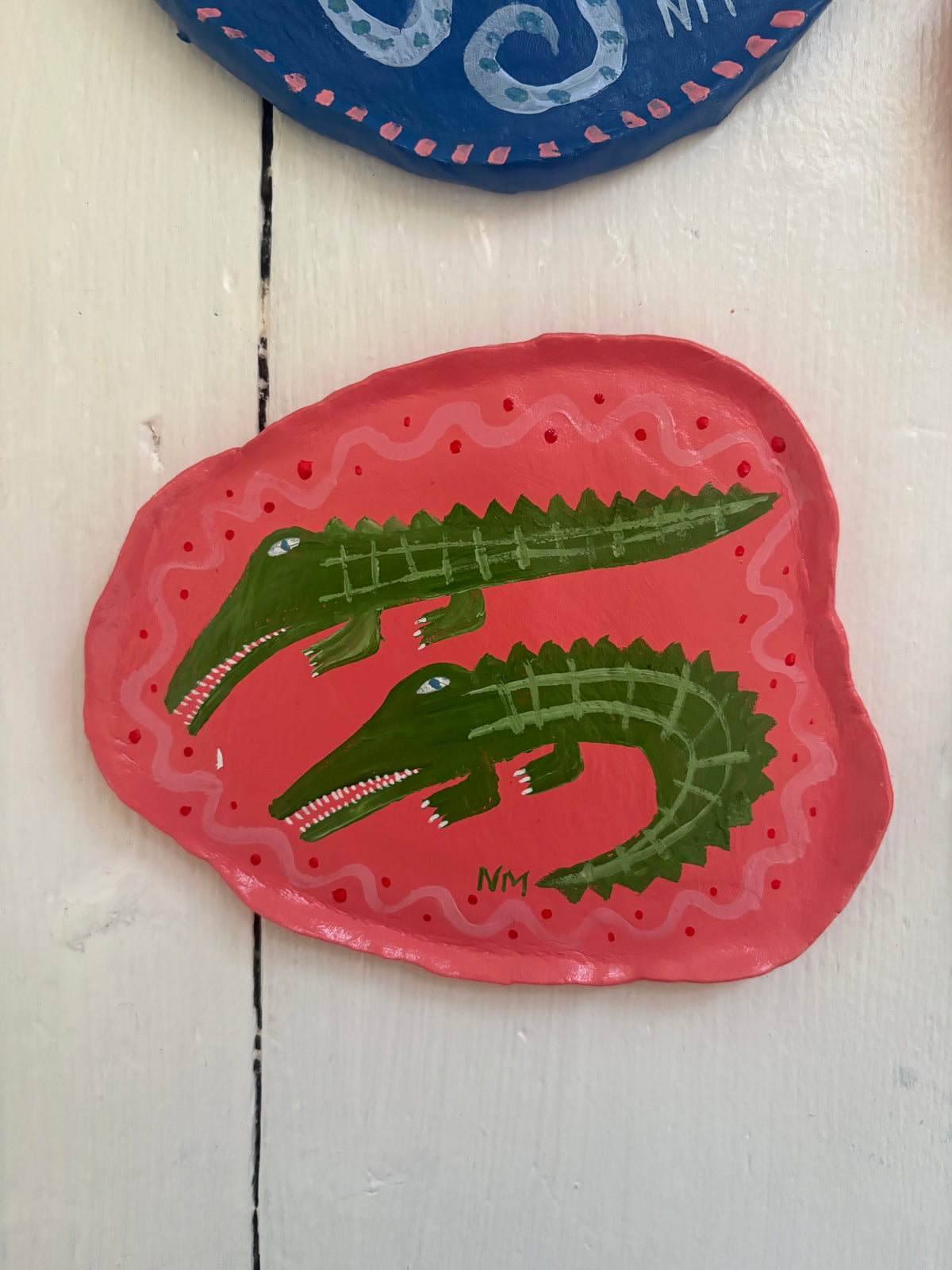 Two crocs on pink wall plate.