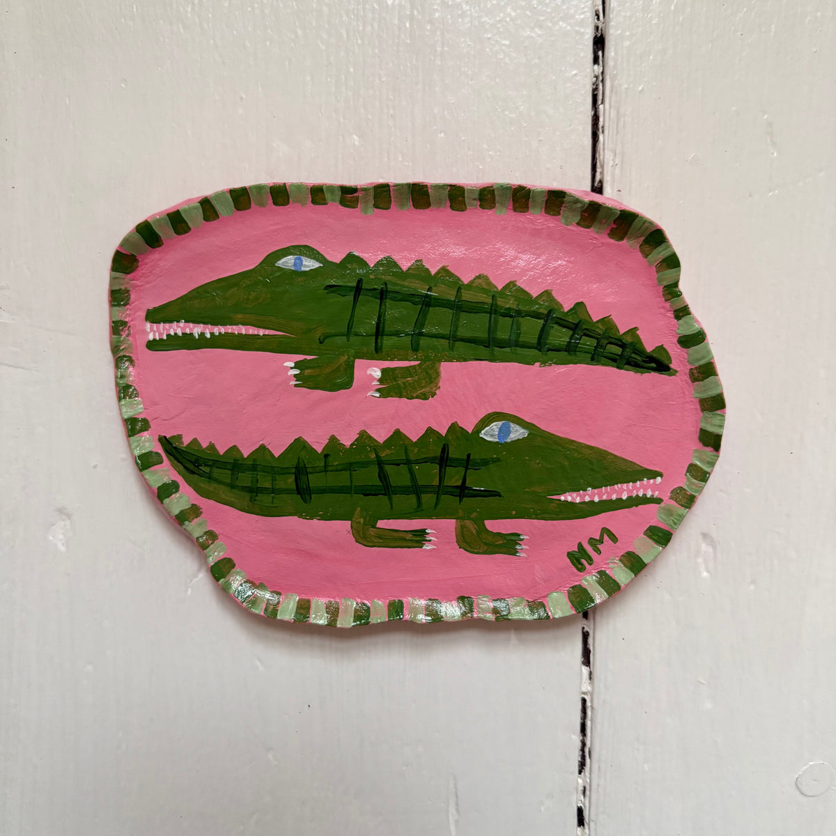 Two crocodiles on pink wall hanging.